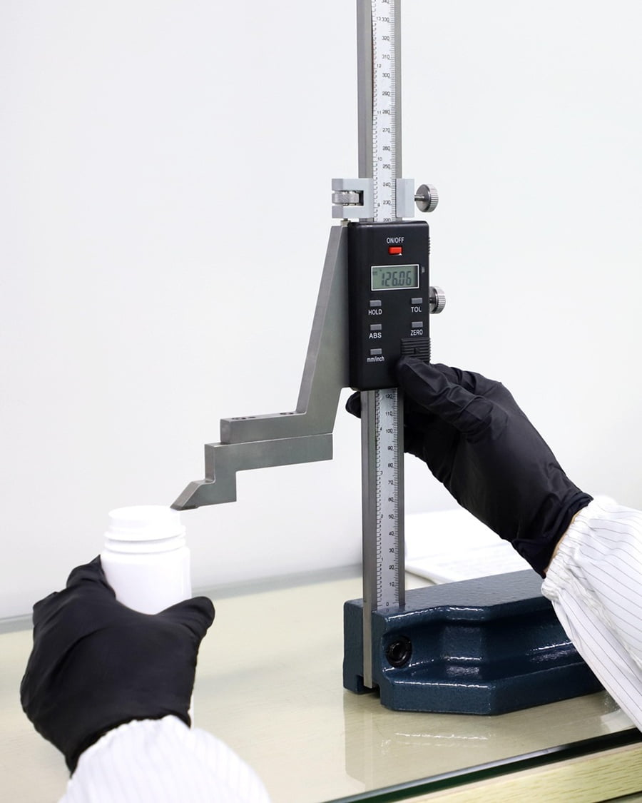 Quality control inspector using precise measurement instruments on cosmetic packaging bottles