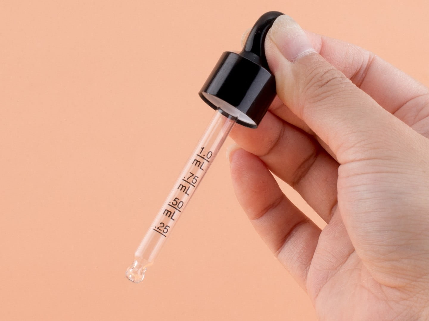 Detailed view of a graduated glass pipette with precise silk-screen printed measurement marks for active serums