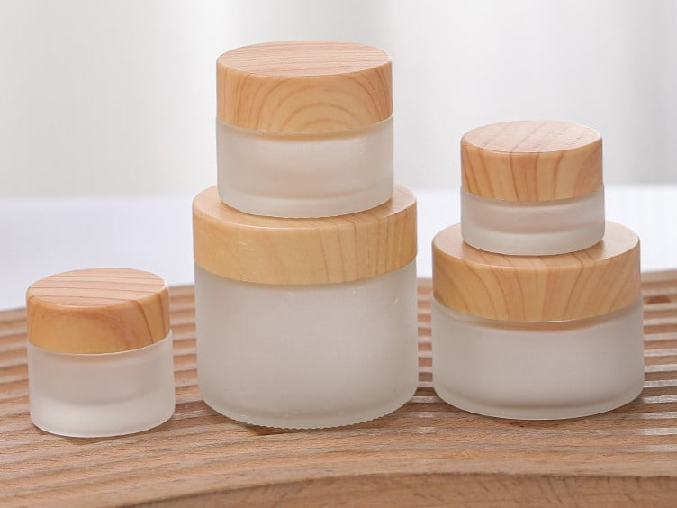 Heavy-wall glass cosmetic jar with thick base and metallic screw cap, showcasing premium skincare packaging