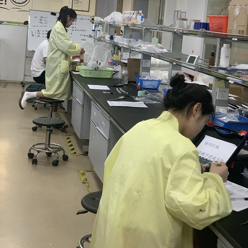 Staff assessing cosmetic packaging samples at laboratory workbenches